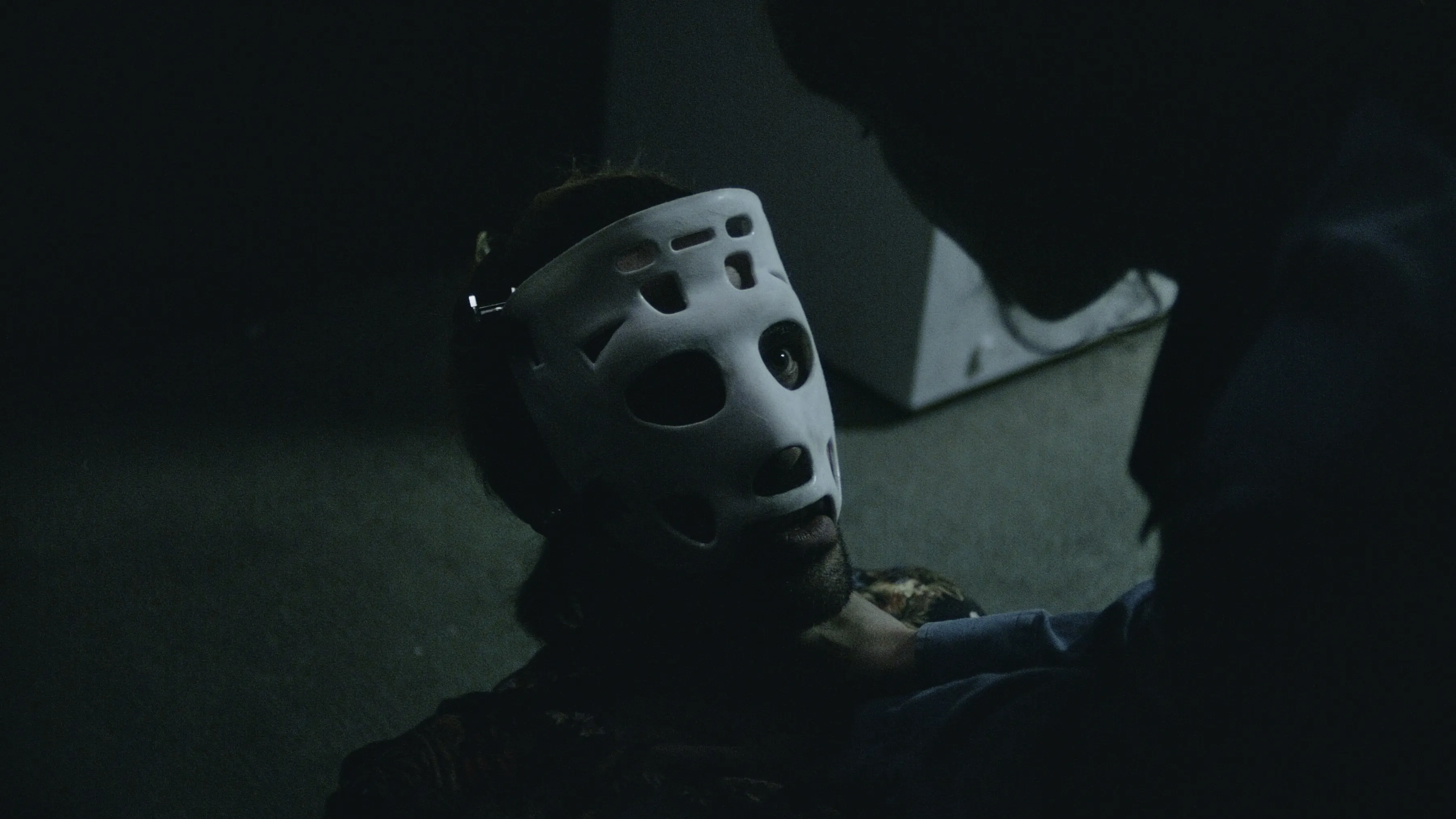 Bild aus dem Film: Mann mit alter Eishockey-Maske wird von Frau gewürgt.